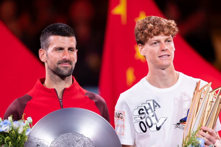 Champion Jannik Sinner of Italy and runner-up Novak Djokovic of Serbia pose with their trophies.