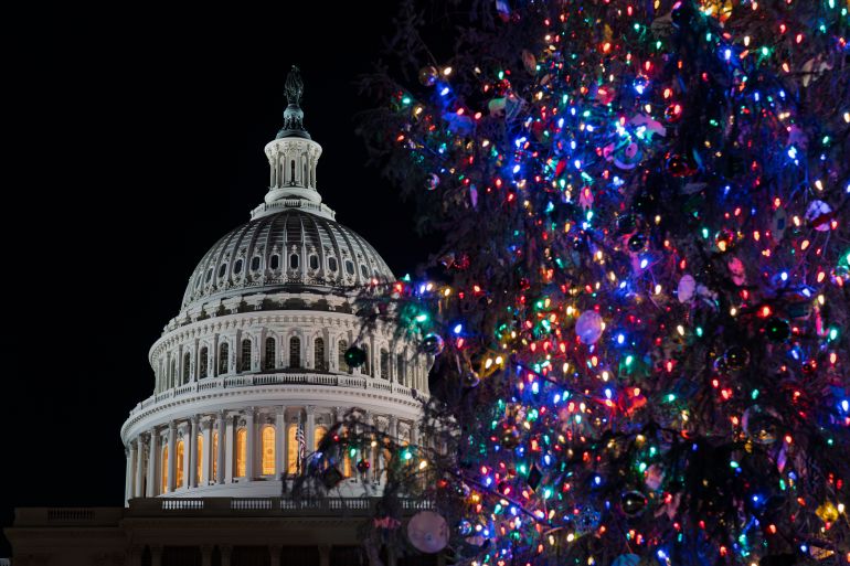 A view of the Capitol dome behind the illuminated Capitol Christmas tree, decorated in multicolor lights.