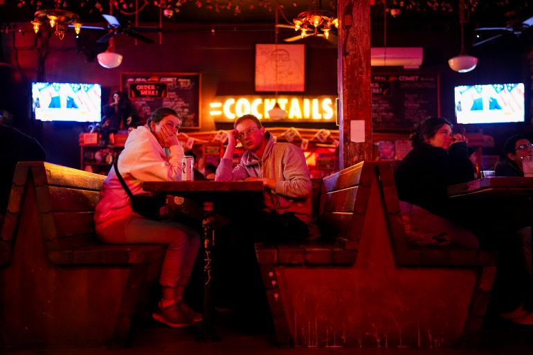 People watch television screens as Donald Trump speaks