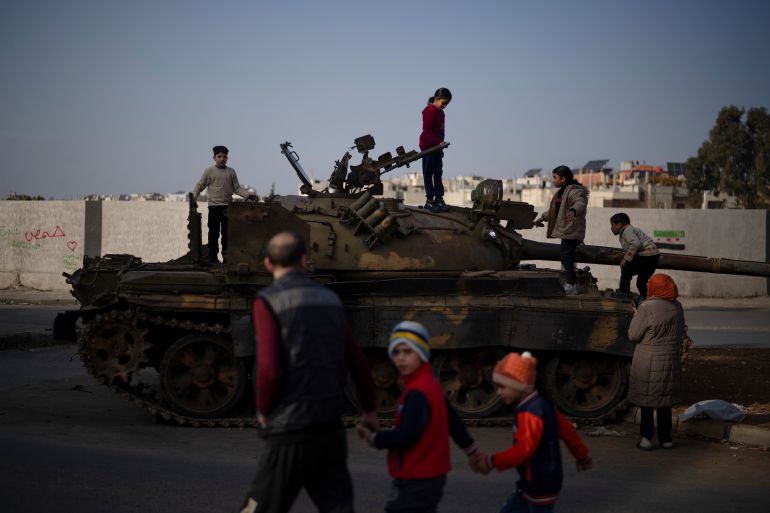 Children on the top of an ousted Syrian government forces tank that was left on a street in an Alawite neighbourhood, in Homs, Syria, Thursday, Dec. 26