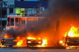 Burning cars in front of a tram.