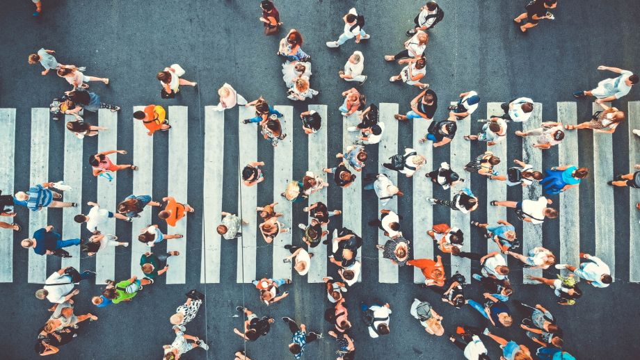 An aerial view of a crowd of people crossing a pedestrian crosswalk