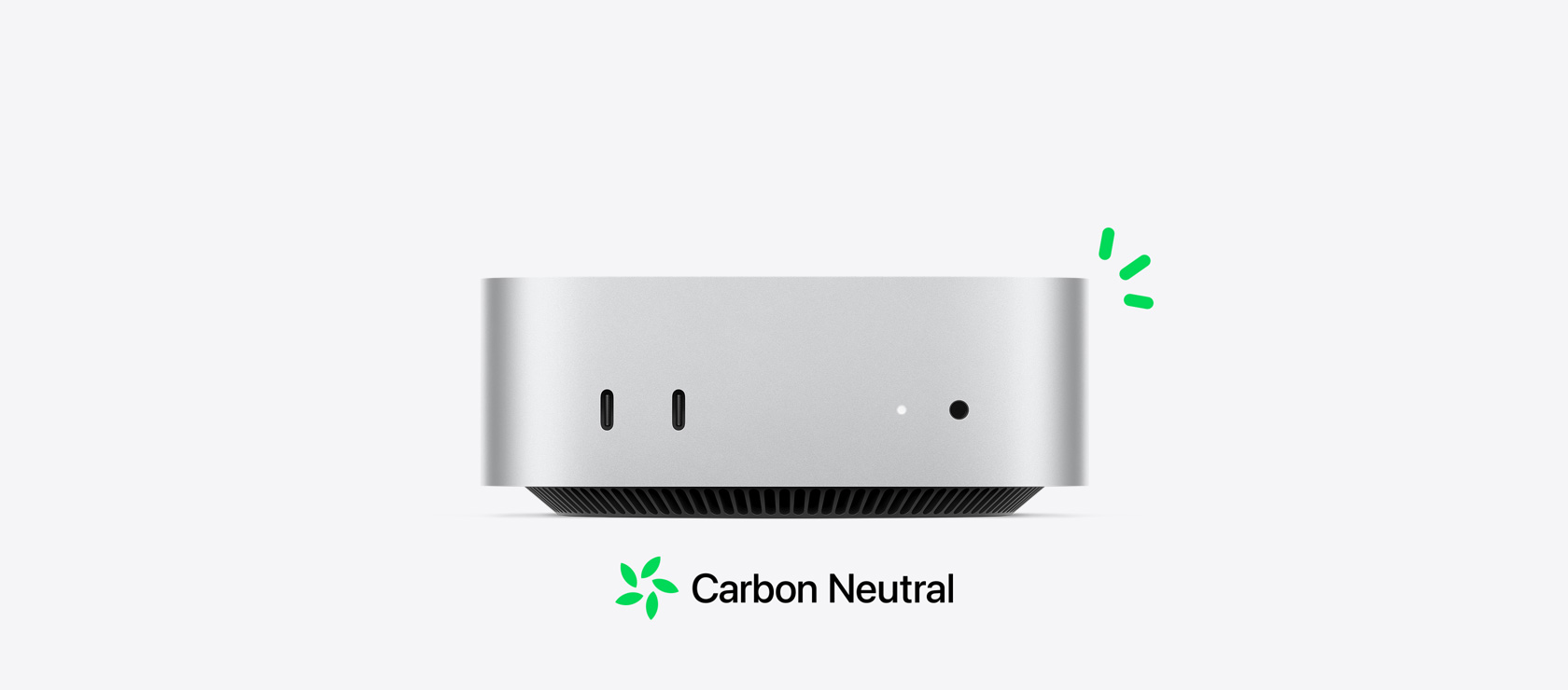 Vedere din față a unui Mac mini argintiu, cu porturile din față și informația despre carbon-neutru ilustrată prin mici accente verzi.