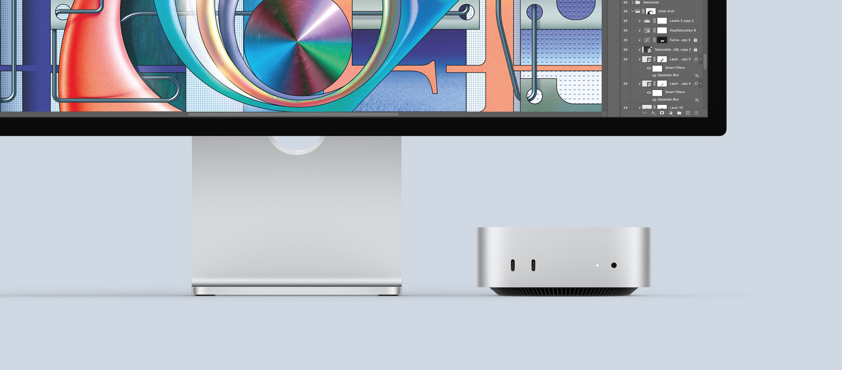 Front view of silver Mac mini showing front ports and indicator light, fitting neatly underneath a Mac monitor showing a colorful screen