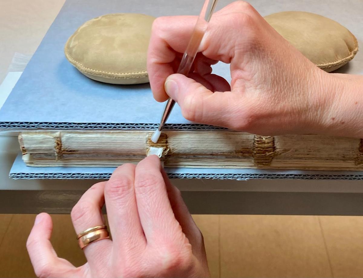 a conservator repairs the ledger containing General Order No. 3