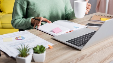 Frau sitzt an Schreibtisch mit Kaffeetasse. Schadet es eurer Gesundheit, wenn ihr im Homeoffice arbeitet? Wir erklären Vor- und Nachteile vom Arbeiten zuhause - und haben Tipps, wie ihr gesund bleibt.  | Bild: colourbox.com