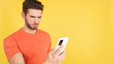 Mann schaut pessimistisch auf sein Handy. Die Prüfung geht sowieso schief, einen Job kriegt ihr nie, alle sind gegen euch. Denkt ihr oft so negativ? Wir erklären, warum manche Menschen eher Pessimisten oder Optimisten sind, was 'pessimistisch' bedeutet - und ob das wirklich immer schlecht ist. | Bild: colourbox.com