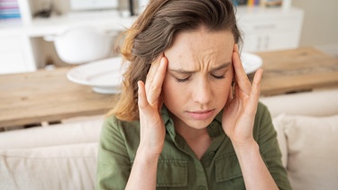 Junge Frau fasst sich an die Schläfen. Habt ihr eine ständige To-do-Liste im Kopf, mit unsichtbaren Aufgaben, an die ihr denken müsst? Diese mentale Belastung nennt man auch Mental Load. Besonders Frauen und Mütter leiden darunter. Das könnt ihr dagegen tun ... | Bild: picture alliance / Zoonar | Channel Partners