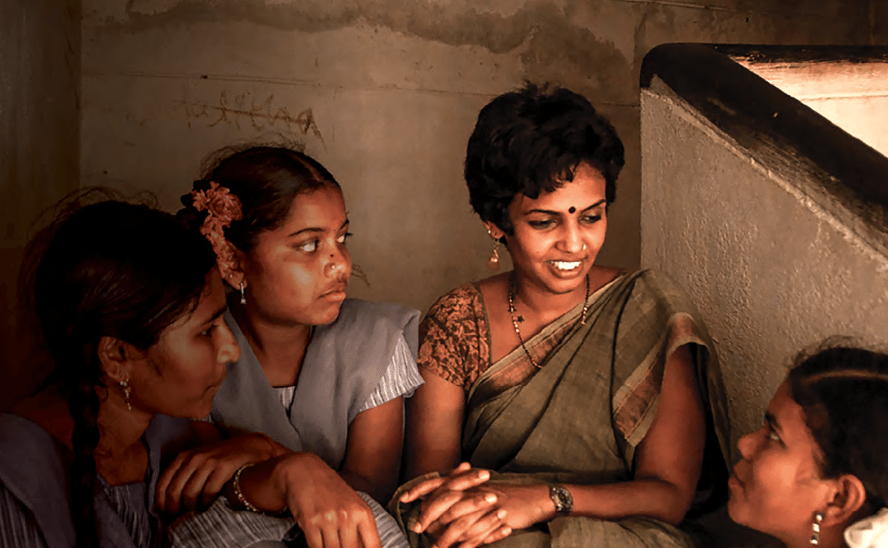 Photo of a woman in a sari talking to three South Asian youths