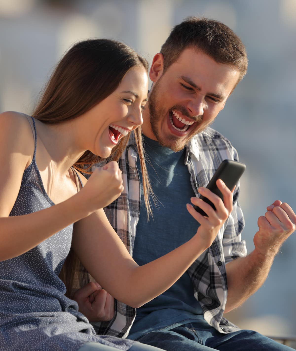 Guy and a girl looking into a phone and rejoicing