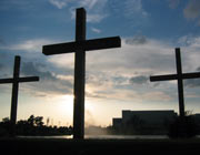 A row of three darkened crosses at sunrise