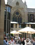 People sitting at cafe tables beneath the façade of Southwark Cathedral