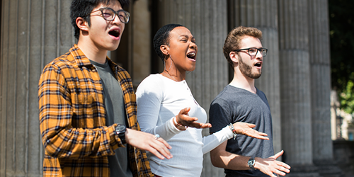 Three students performing outside the Victoria Rooms.