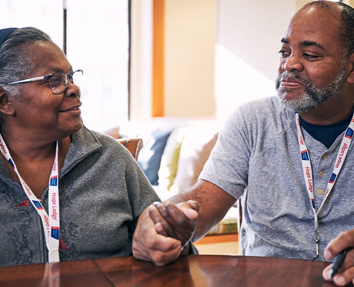 Couple holding hands at a table wearing Hope Lodge lanyards