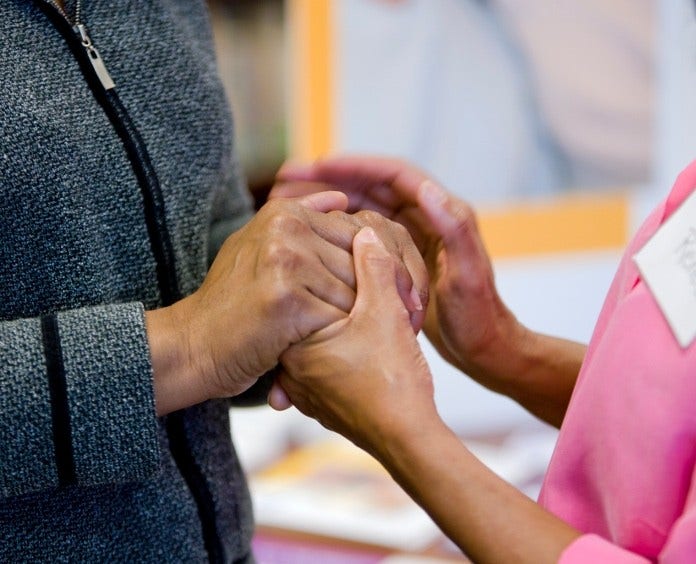 two women clasping hands