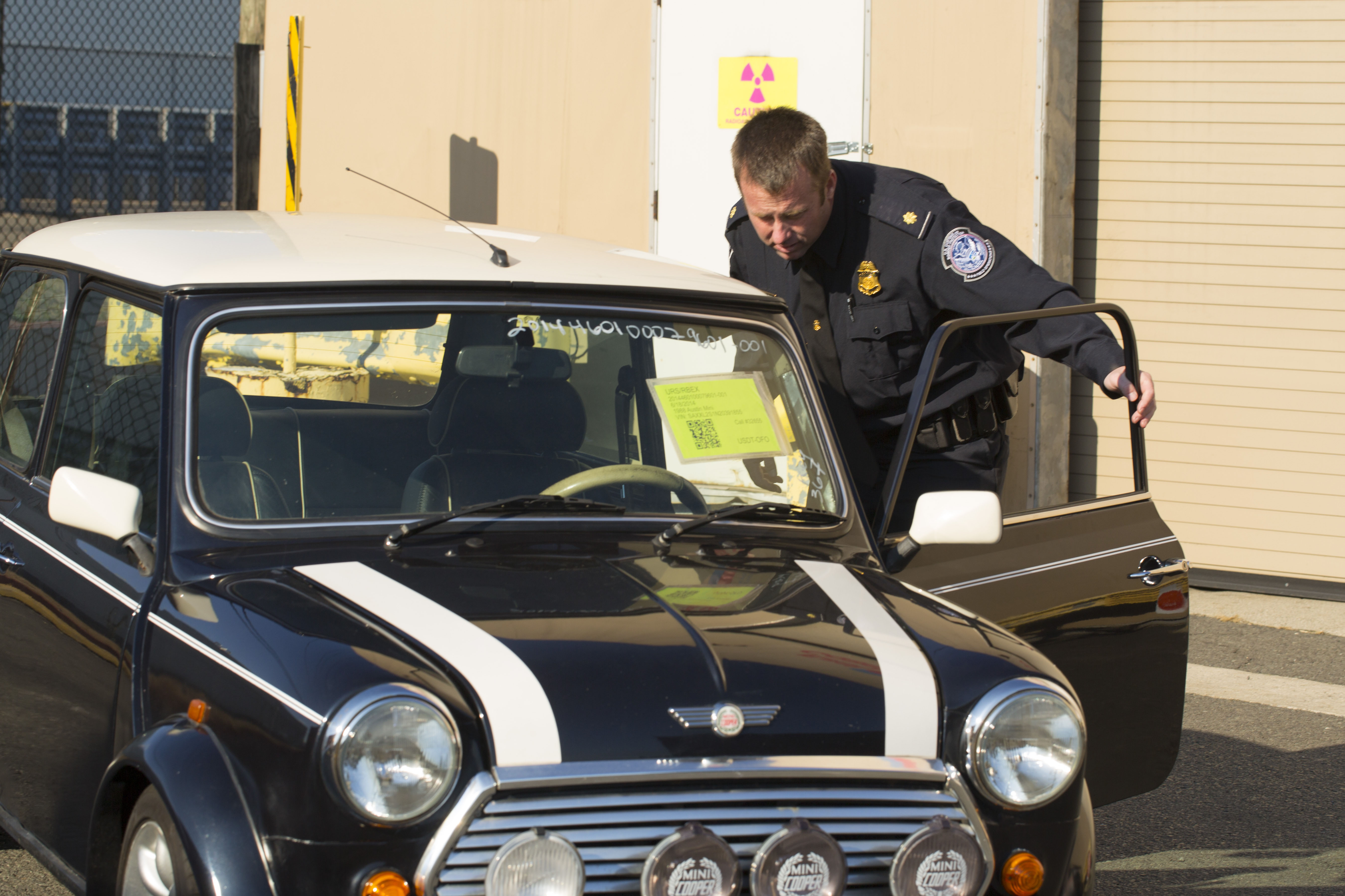 A Customs and Border Protection Officer inspects a Mini Cooper that arrived to Port Elizabeth NJ that had numerous violations associated with it related to importation. This vehicle will be destroyed as a result. Photo Credit: James Tourtellotte