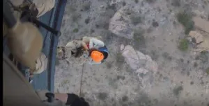 An AMO aircrew rescue specialist is hoisted into the aircraft with an injured migrant