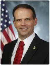 Acting Chief Operating Officer James McCament positioned in front of the American flag.