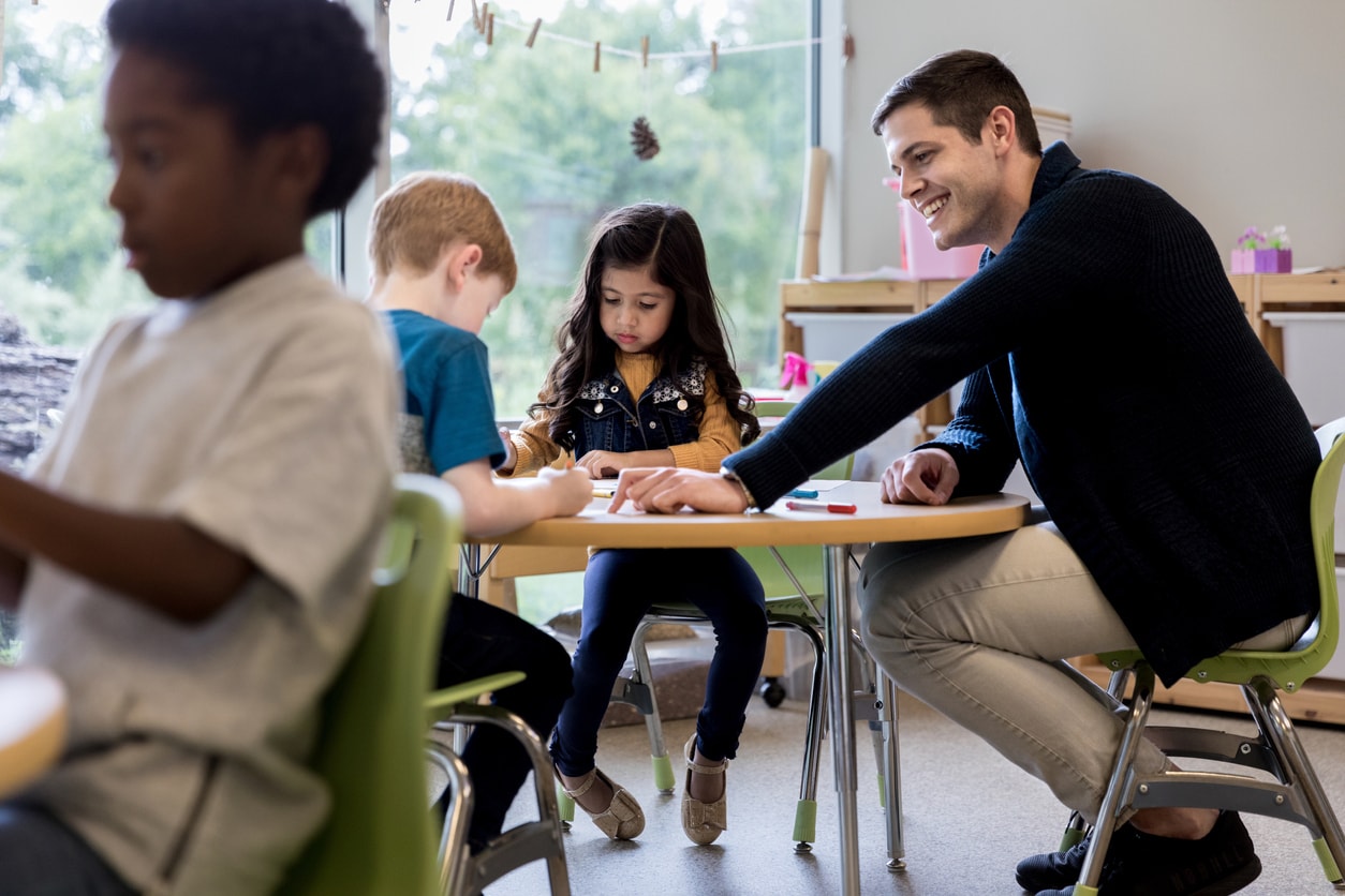 A parent volunteer helps out in his son or daughter's kindergarten art class.