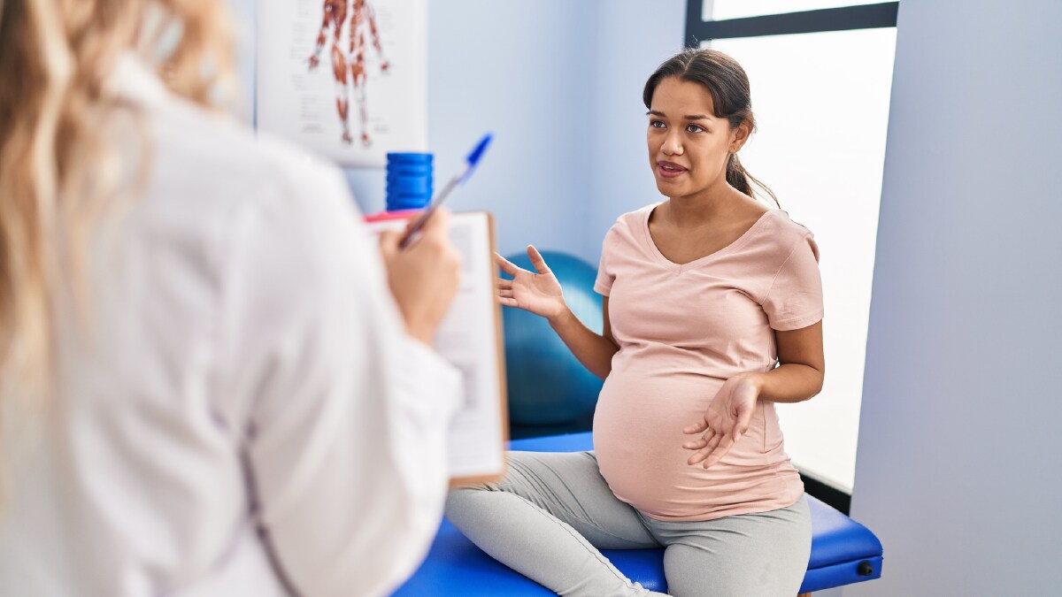 The image shows a pregnant patient talking to a clinician.