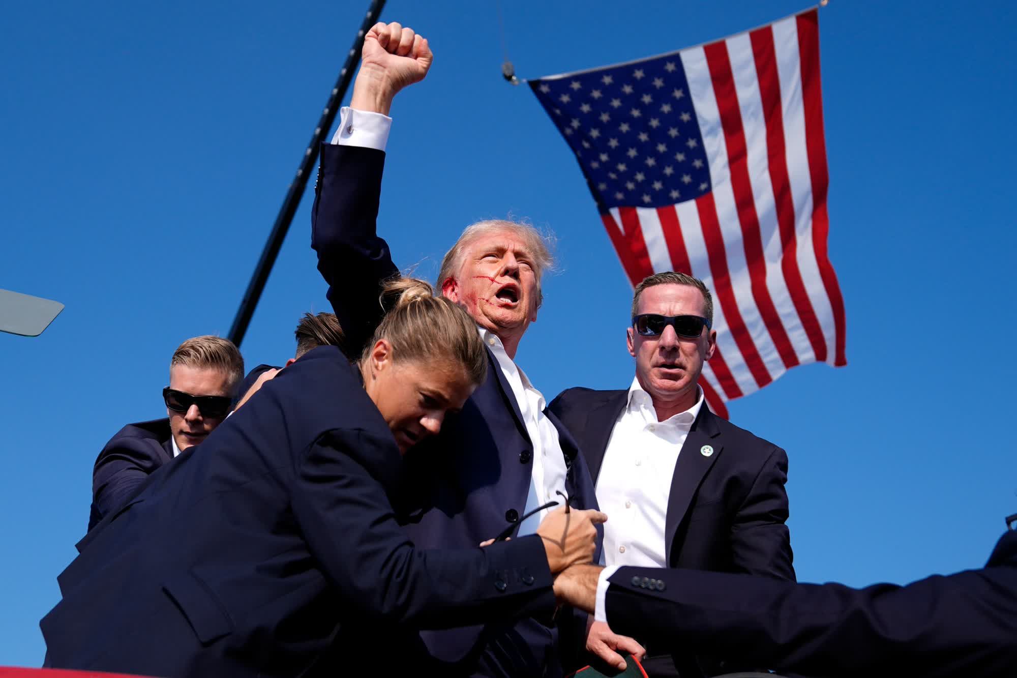 Former President Donald Trump, with blood on his face, raises his fist to the crowd as he is surrounded by Secret Service agents at his campaign rally in Butler, Pennsylvania, on Saturday. (Evan Vucci/AP)