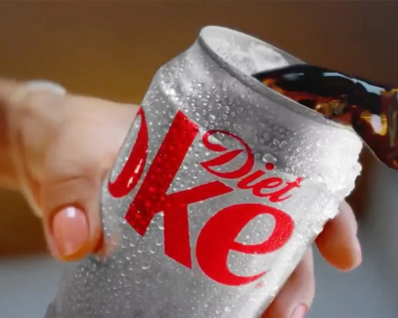 Can of diet coke dripping with condensation being poured out