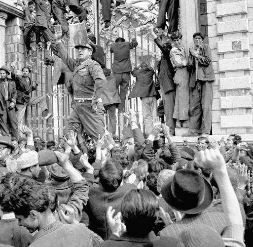 An officer demonstrating for the Shah of Iran strikes a typical Mussolini pose as he harangues crowds in front of Parliament Gate in Tehran on March 3, 1953. He wears a photo of the Shah on his hat.