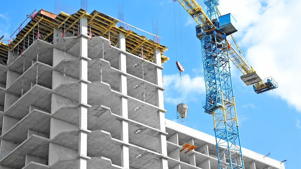 Crane and building under construction against blue sky