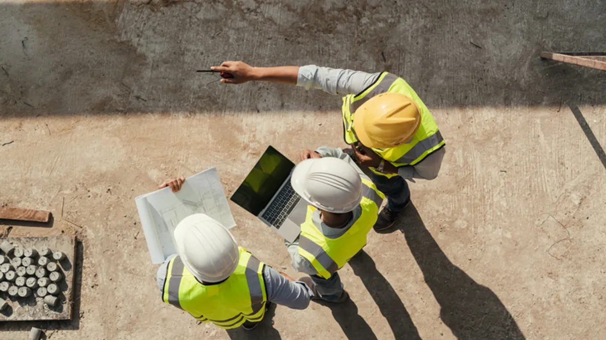 construction workers look at a laptop