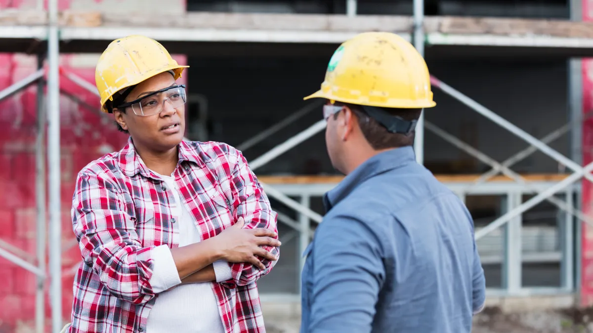 A stock photo shows two construction workers having a difficult conversation.