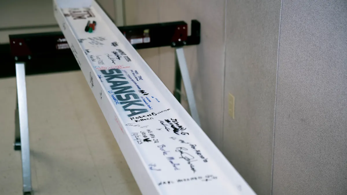 A white steel beam covered in signatures.