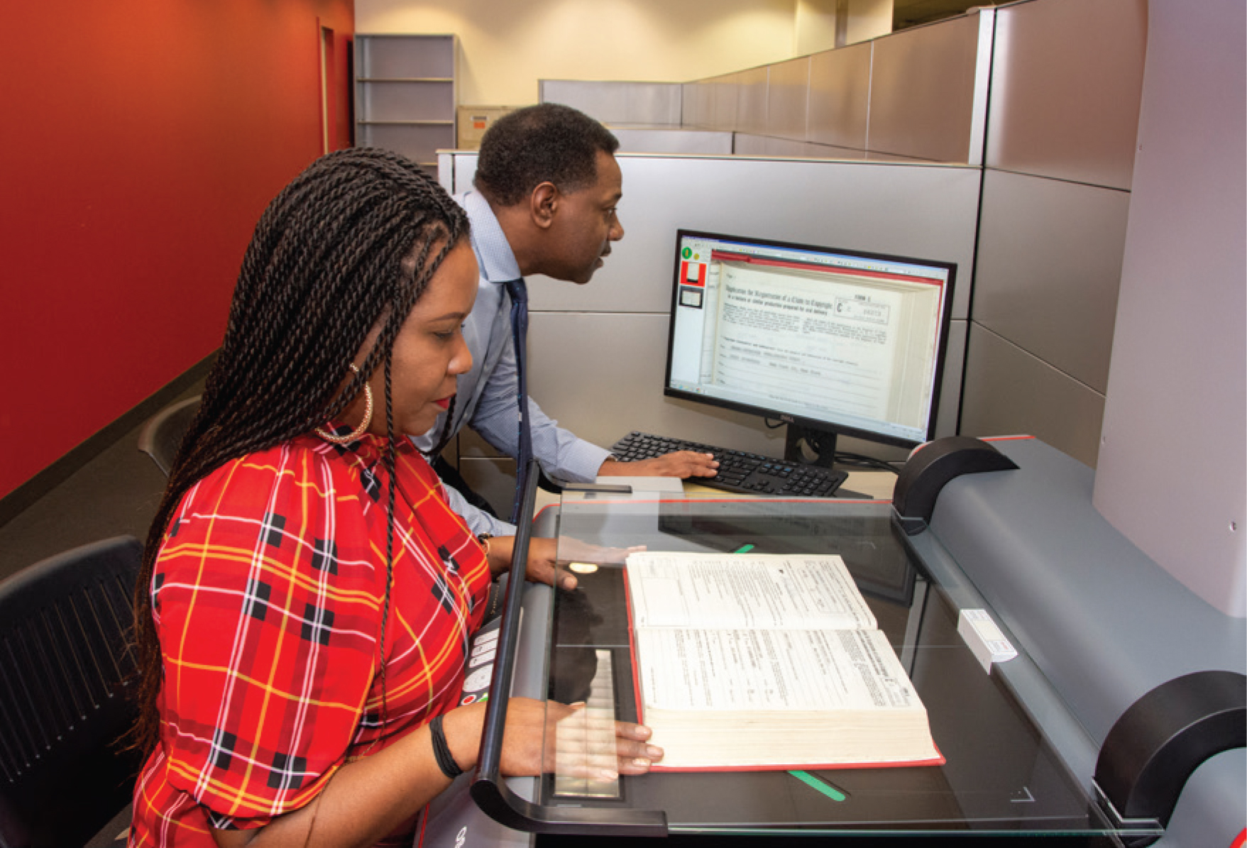 Staff at computer and staff scanning book