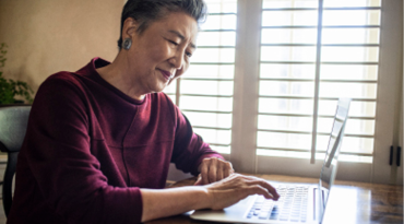 Woman using a laptop while sitting at her dining room table