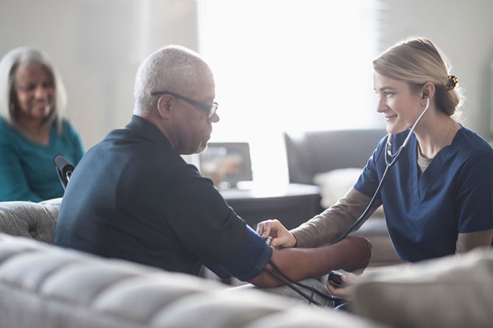 Nurse in skilled nursing facility taking a man's blood pressure