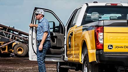 man exiting his John Deere branded truck. 