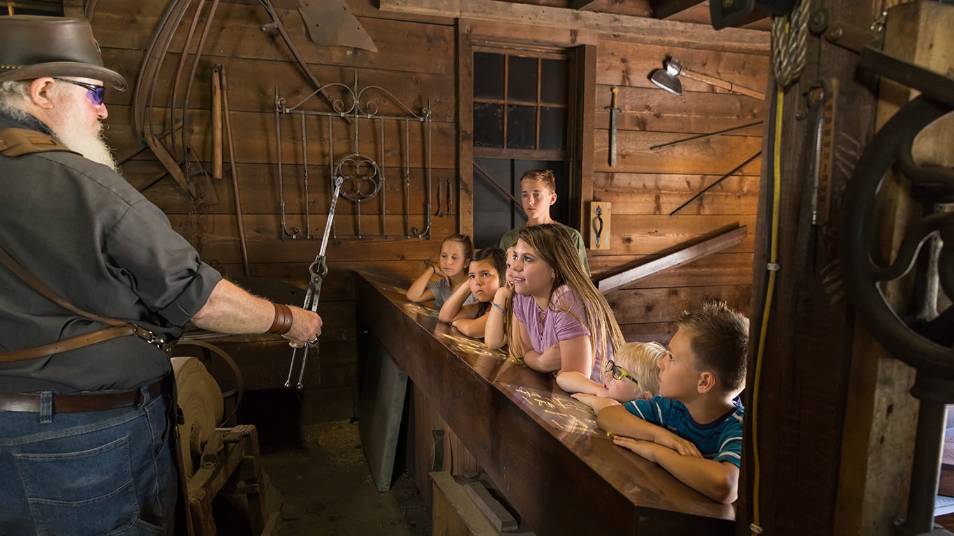 The John Deere Blacksmith is doing a live demonstration for a group of children