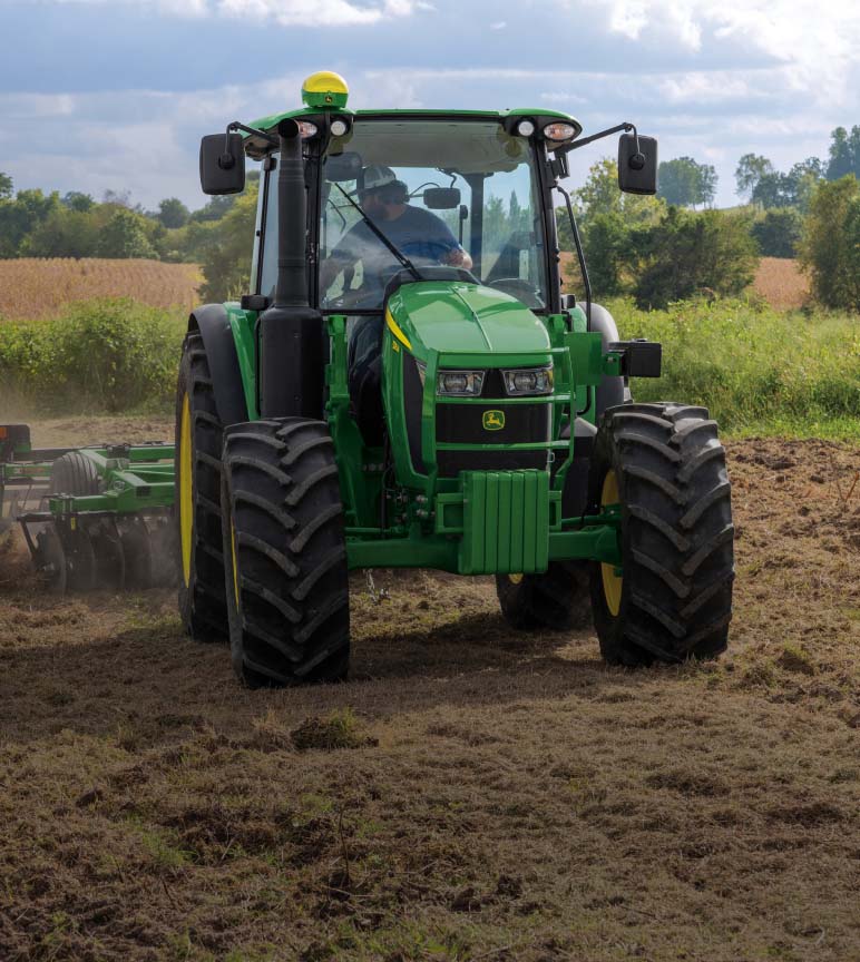 5 Series Tractor in use, pulling attachment in field.