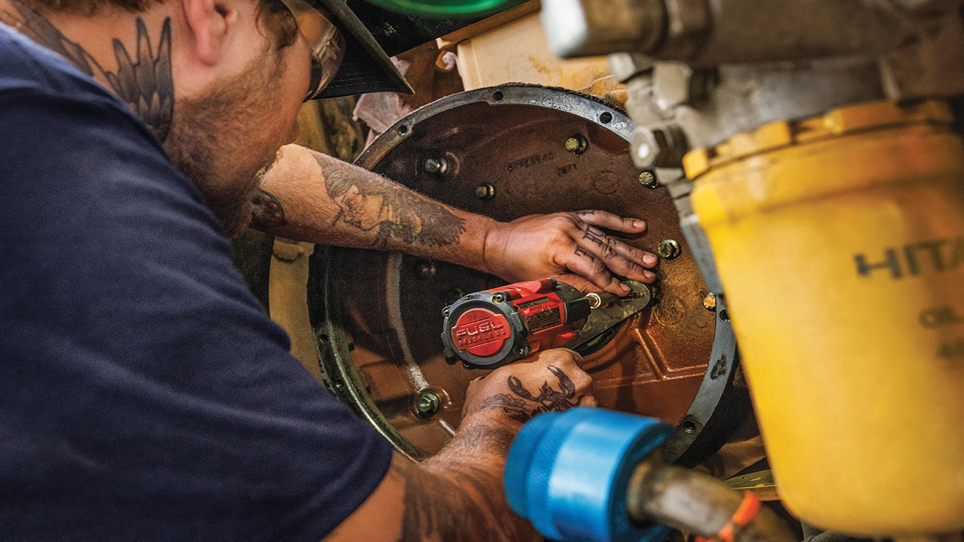 A service technician rebuilding an excavator flywheel.