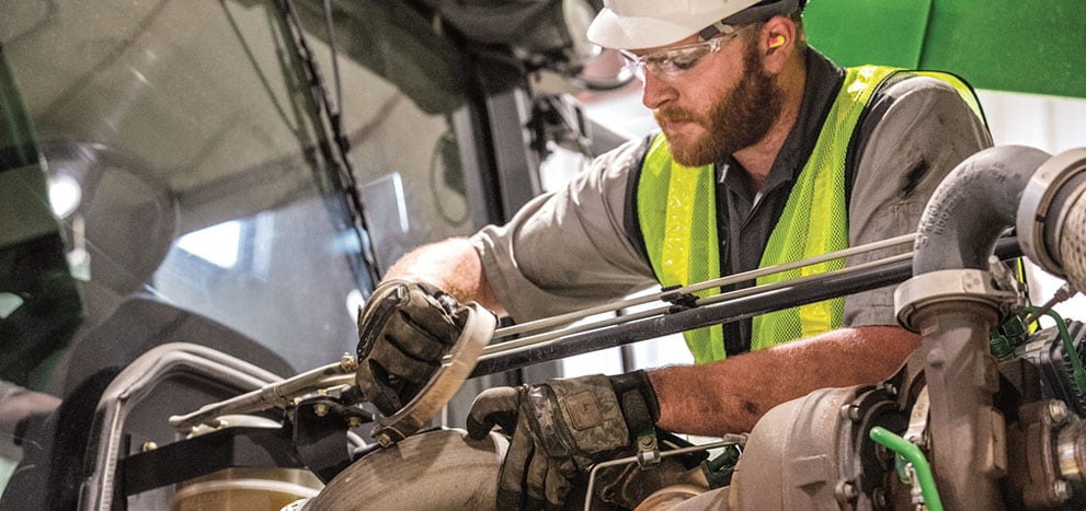 A technician works on a John Deere tractor