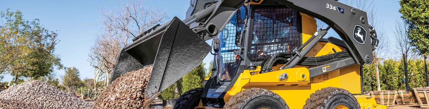 John Deere 334P skid steer loader dumps a load of gravel from its bucket