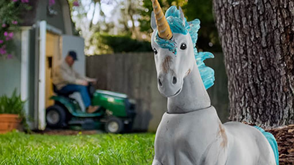 a unicorn figurine with a man on mower in the background