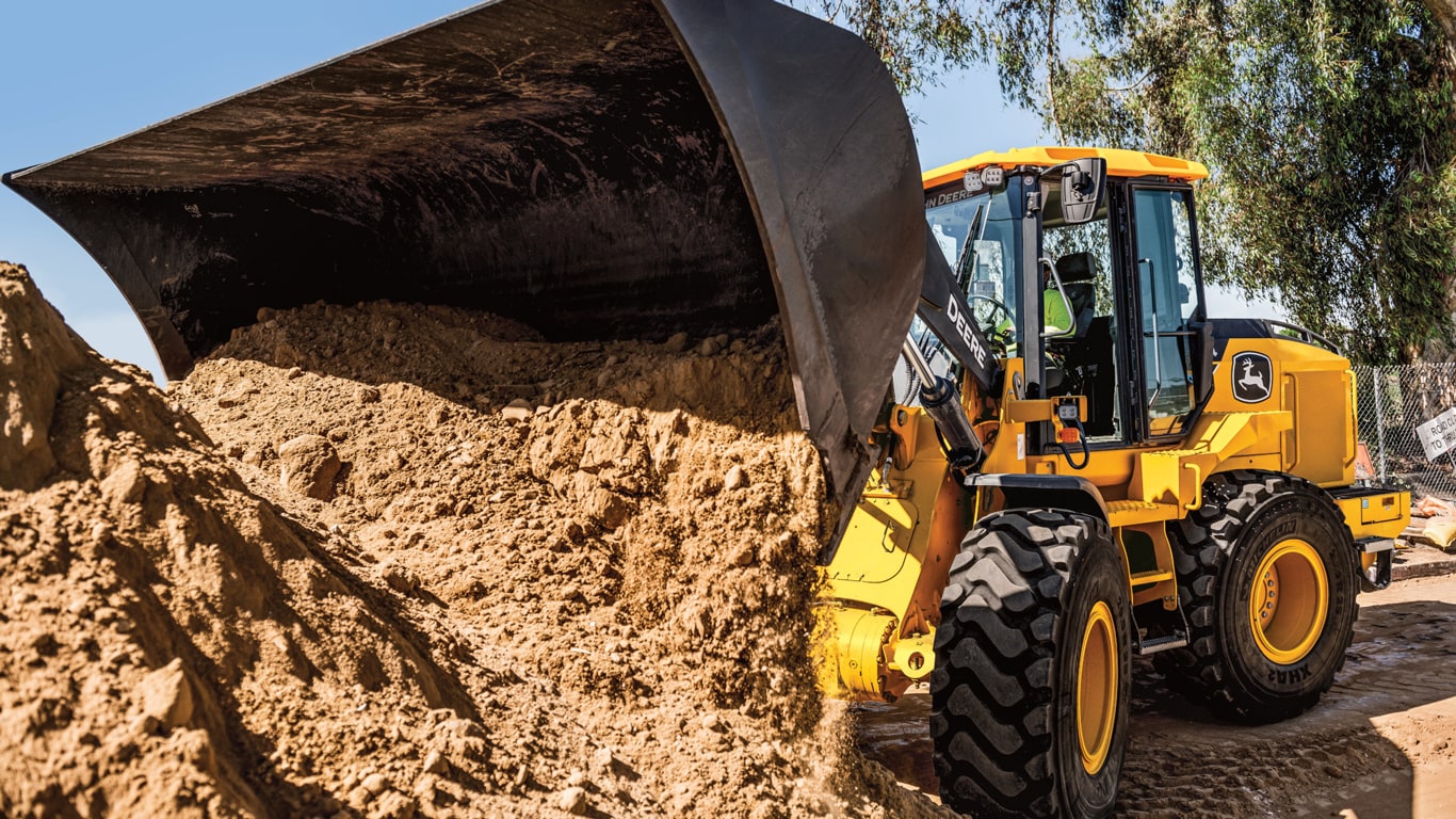 John Deere 544 P-Tier Wheel Loader dumps a bucket of dirt