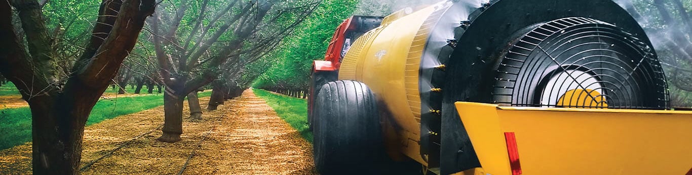 Orchard sprayer powered by a John&nbsp;Deere engine with a row of trees.