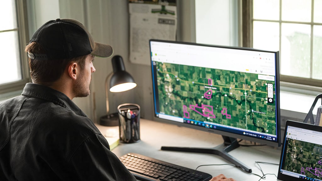 Man in front of computer looking at field screens