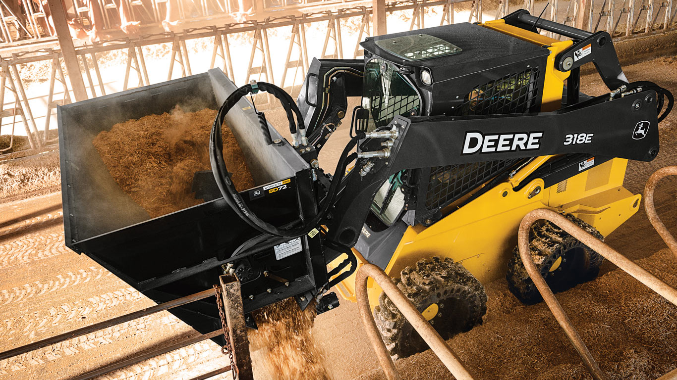 bucket side discharge attachment on a skid steer in a barn