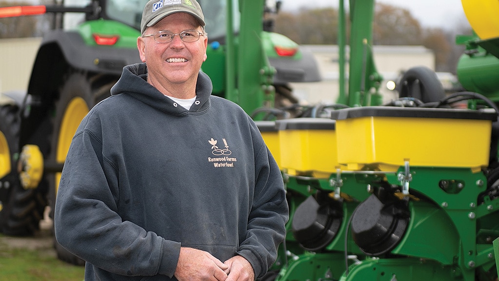 Smiling farmer standing in front of green and yellow John Deere equipment