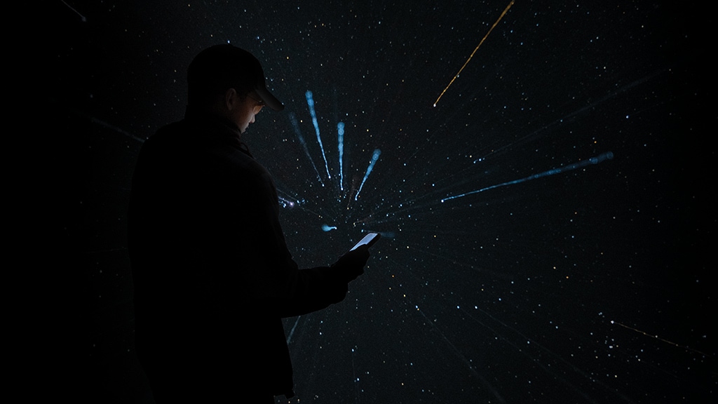 Shooting stars above a person looking at an illuminated mobile phone at night 