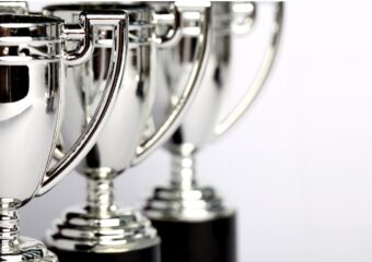 Silver trophy cups aranged in a diagonal line, from front left toward background in center.