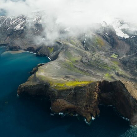 Aerial view of coastline in a colder weather climate along the sea. Snow is visible on mountain slopes next to the sea.