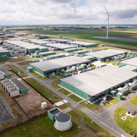 Aerial view of a data center with wind turbines nearby.